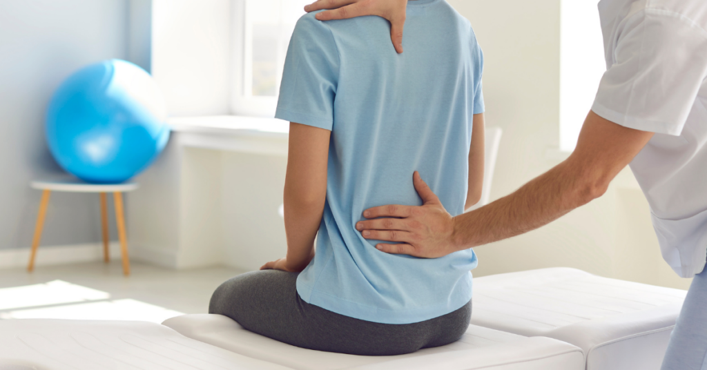 Physical therapist assisting a patient with a lower back stretch to relieve pain and improve mobility in a clinical setting.